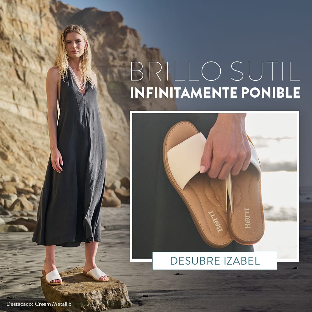 Brillo Sutil. Infinitamente Ponible. Una mujer parada en la playa usando la sandalia tipo slide Izabel destacada en Met&aacute;lico Crema. Descubre Izabel.